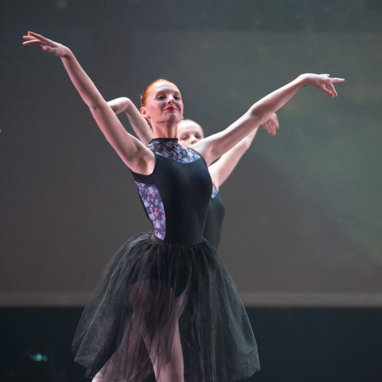 Twee Ballet danseresen in een maillot pak en tutu met de armen naar boven gestrekt.