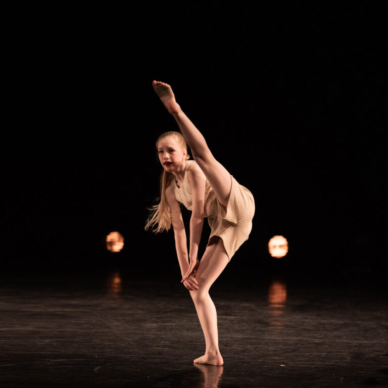 Een danseres van Modern Dans strekt haar been in de lucht.