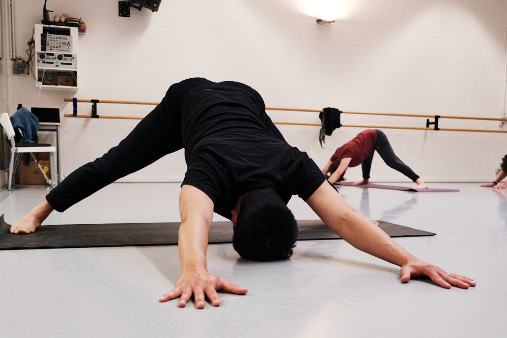 Yogaleraar in een yoga houding tijdens een les in Ndigo Roeselare.